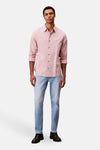Slim jeans van lichtblauw denim van Calvin Klein, gedragen met een roze gestreept overhemd en zwarte schoenen.