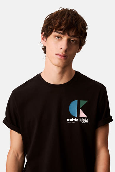 T-shirt à manches courtes noir de Calvin Klein, avec un logo géométrique sur la poitrine et des manches roulées.
