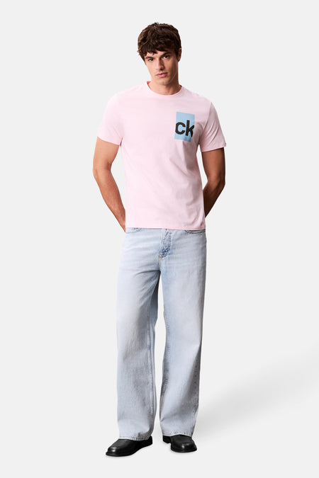 Roze T-shirt met korte mouwen van Calvin Klein, met vierkant logo op de voorkant, gedragen met een wijde spijkerbroek.