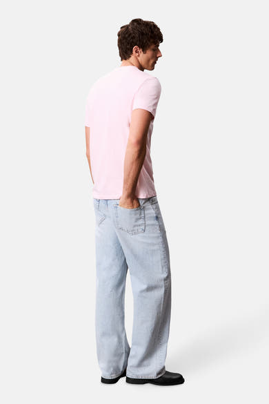 T-shirt à manches courtes rose de Calvin Klein, porté avec un jean décontracté et des chaussures noires.
