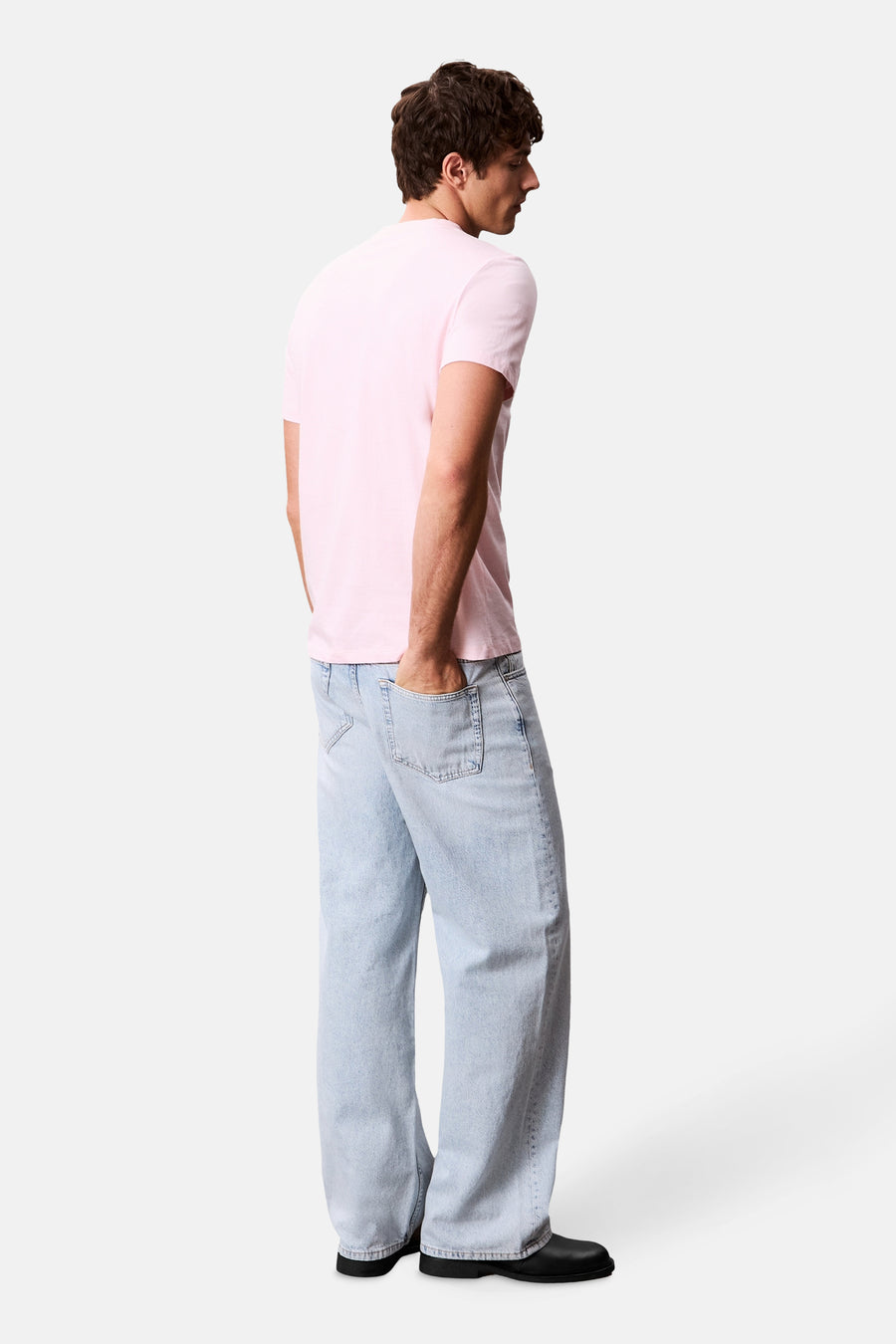 T-shirt à manches courtes rose de Calvin Klein, porté avec un jean décontracté et des chaussures noires.