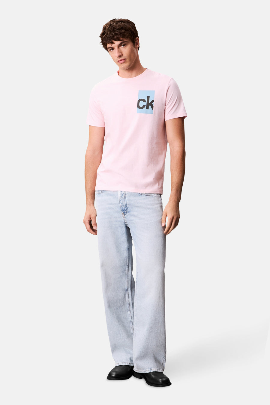 T-shirt rose à manches courtes de Calvin Klein, avec logo carré sur la poitrine, porté avec un jean ample.
