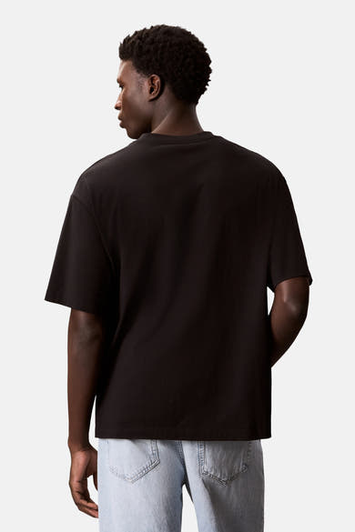 T-shirt noir à manches courtes de Calvin Klein, porté avec un jean taille basse, vue de dos.