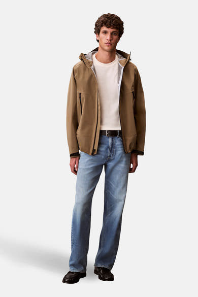 T-shirt à manches courtes jaune de Calvin Klein, porté avec une veste marron ouverte et un jean bleu