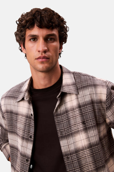 Chemise à manches longues grise à carreaux de Calvin Klein avec un t-shirt noir en dessous.
