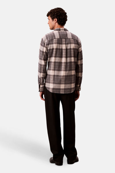 Chemise à manches longues grise à carreaux de Calvin Klein, portée avec un pantalon noir.