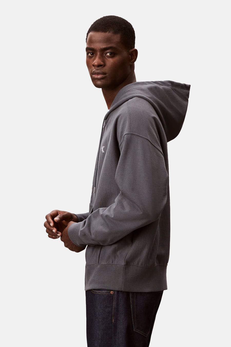 Blauwe Calvin Klein rits-sweatshirt, gedragen met een spijkerbroek, van opzij gezien.