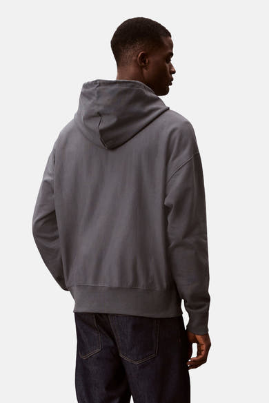 Blauwe Calvin Klein sweatvest met capuchon, gedragen met een donkere spijkerbroek, achtergezicht.