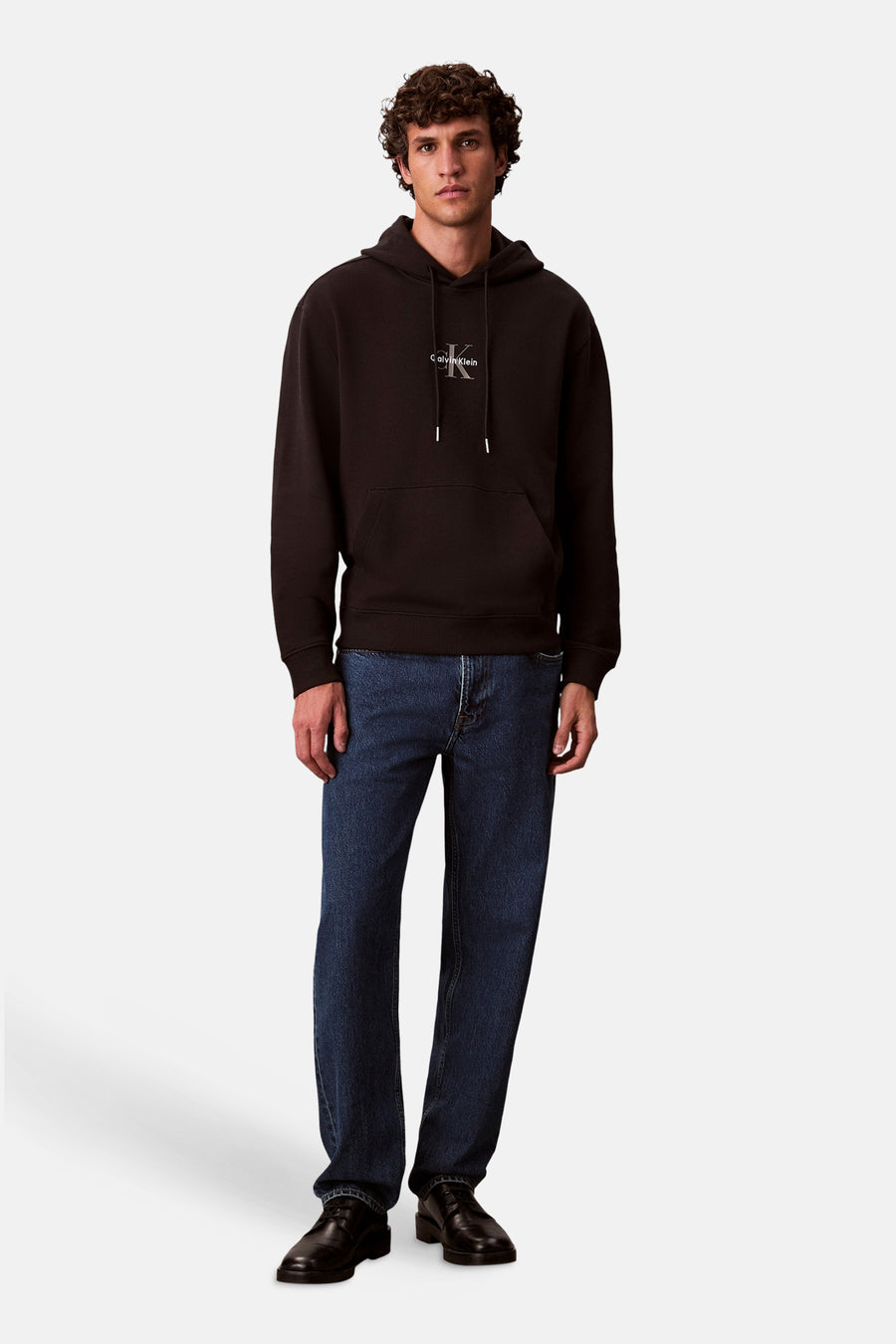 Zwarte Calvin Klein hoodie met logo op de voorkant, gedragen met een blauwe jeans en zwarte schoenen.
