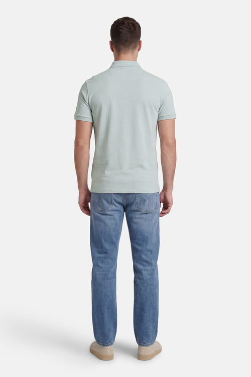 Polo à manches courtes bleu de Calvin Klein, porté avec un jean et des chaussures décontractées, vue arrière.
