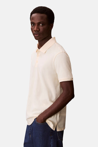Oranje poloshirt met korte mouwen van Calvin Klein, gedragen met een blauwe spijkerbroek.