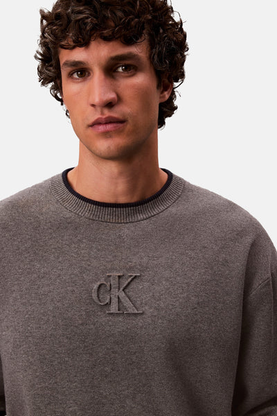 Grijze rondehals trui van Calvin Klein, met toon-op-toon reliëflogo op de voorkant.