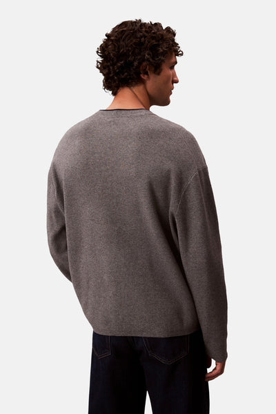 Pull à col rond gris par Calvin Klein, porté avec un jean foncé.