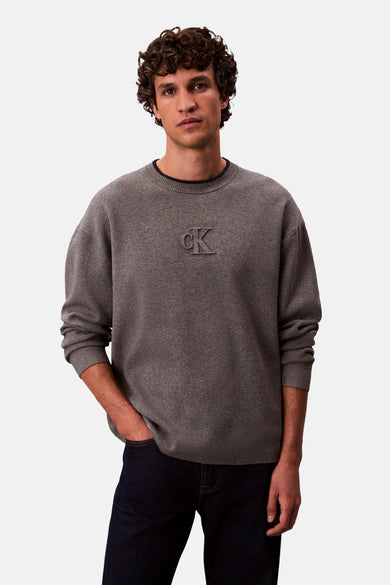 Grijze rondehals trui van Calvin Klein, met toon-op-toon logo op de voorkant en lange mouwen.