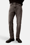 Slim jeans in middengrijs denim van Calvin Klein, gedragen met een zwarte trui en zwarte leren schoenen, in zijaanzicht.