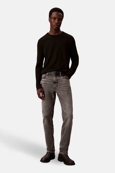 Slim jeans in middengrijs denim van Calvin Klein, gedragen met een zwarte trui en leren enkellaarsjes.