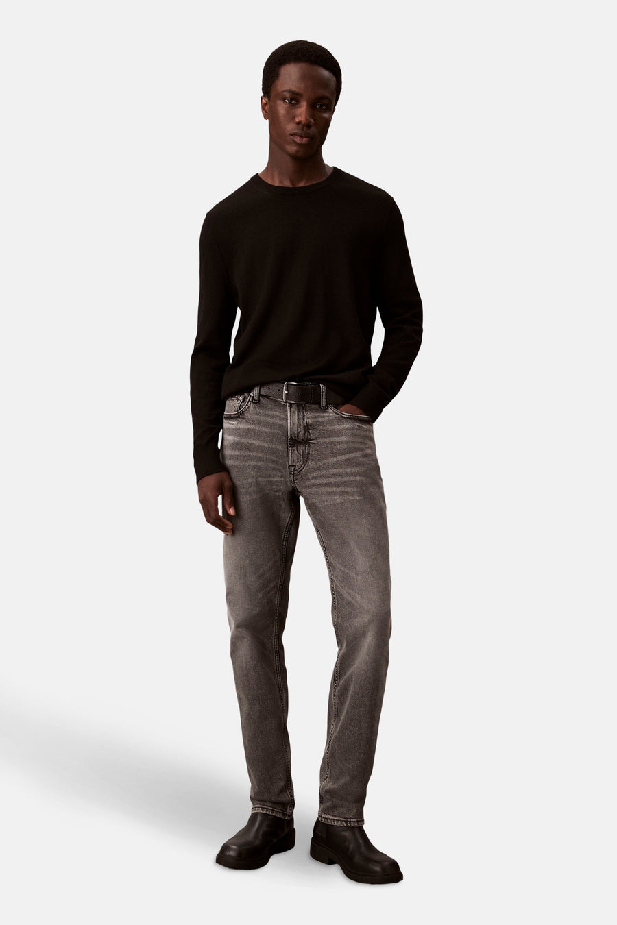 Slim jeans in middengrijs denim van Calvin Klein, gedragen met een zwarte trui en leren enkellaarsjes.