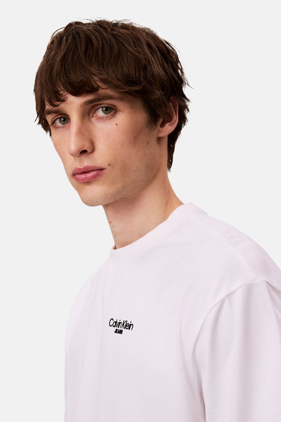Wit T-shirt met korte mouwen van Calvin Klein Jeans, gedragen door een man met bruin haar.