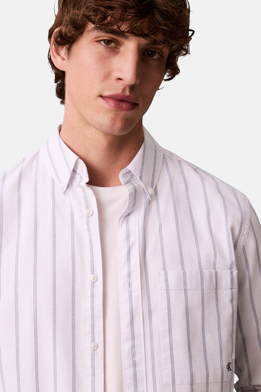 Chemise blanche à rayures verticales de Calvin Klein, avec poche poitrine et logo discret.