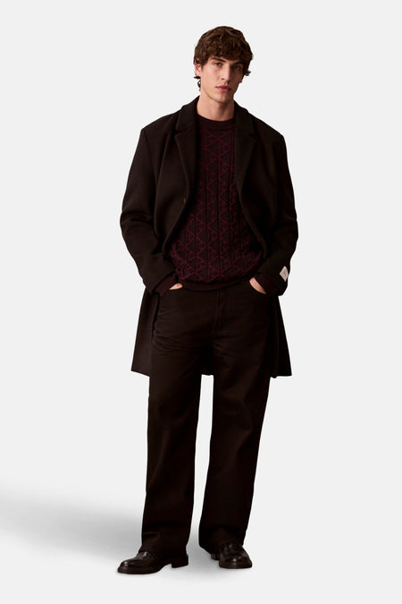 Sweat-shirt noir à col rond de Calvin Klein porté avec un manteau long et un pantalon noir.