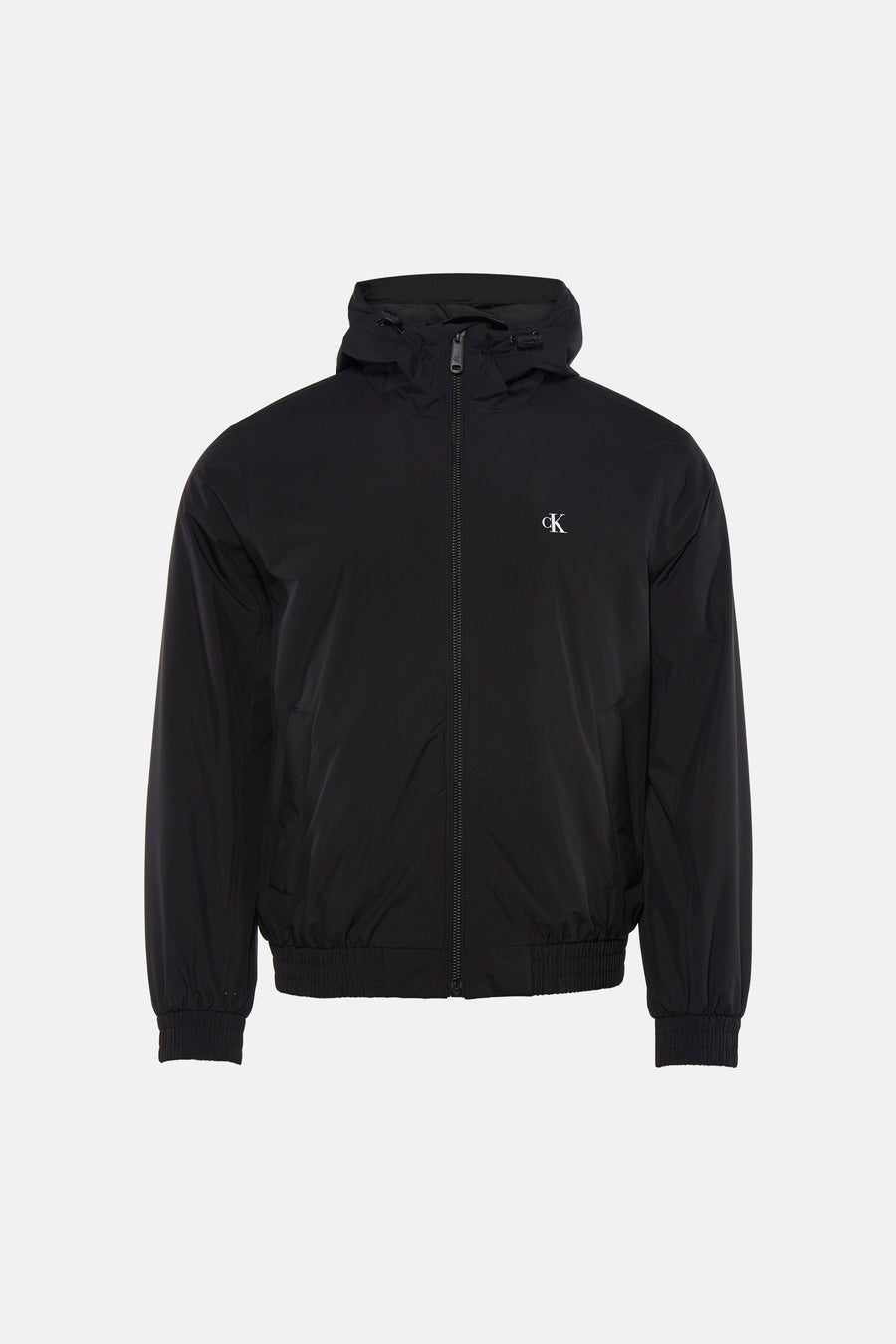 Zwarte regenjas van Calvin Klein, gedragen met een zwart T-shirt en een lichtgrijze spijkerbroek.