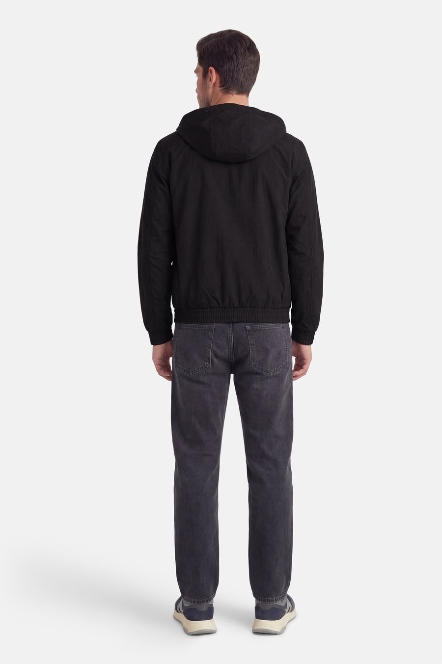Zwarte regenjas van Calvin Klein, met capuchon, gedragen met een grijze jeans en sneakers.