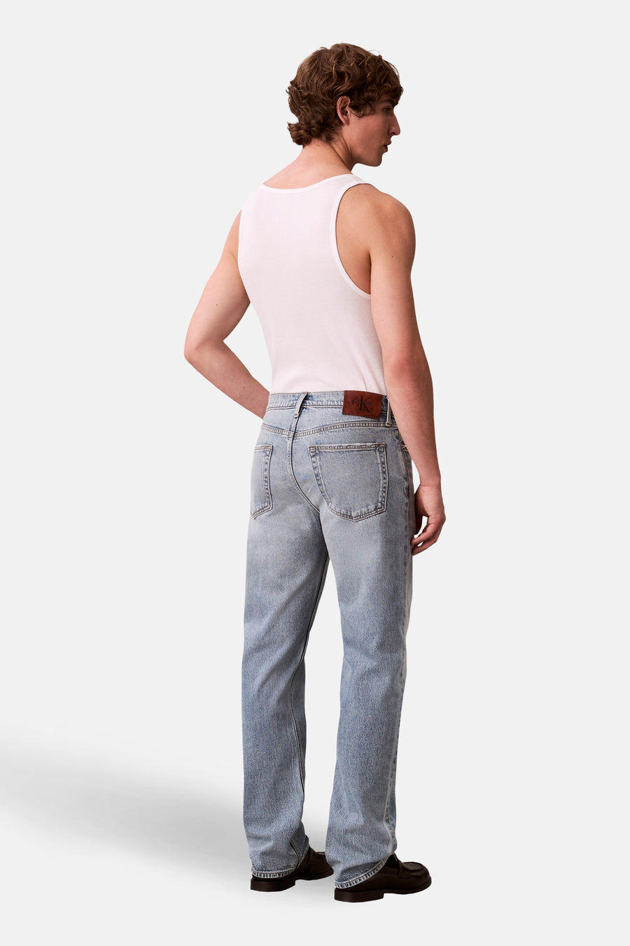 Rechte lichtblauwe spijkerbroek van Calvin Klein, gedragen met een witte tanktop en zwarte loafers.