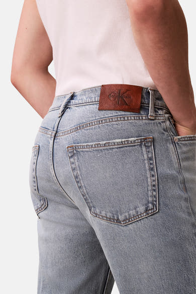 Rechte lichtblauwe spijkerbroek van Calvin Klein, met bruin leren patchdetail op de taille.