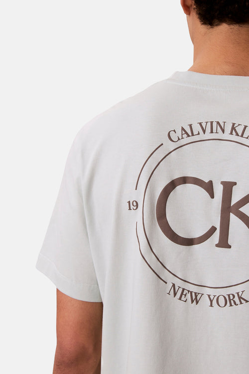 T-shirt bleu à manches courtes de Calvin Klein, avec un logo marron au dos.