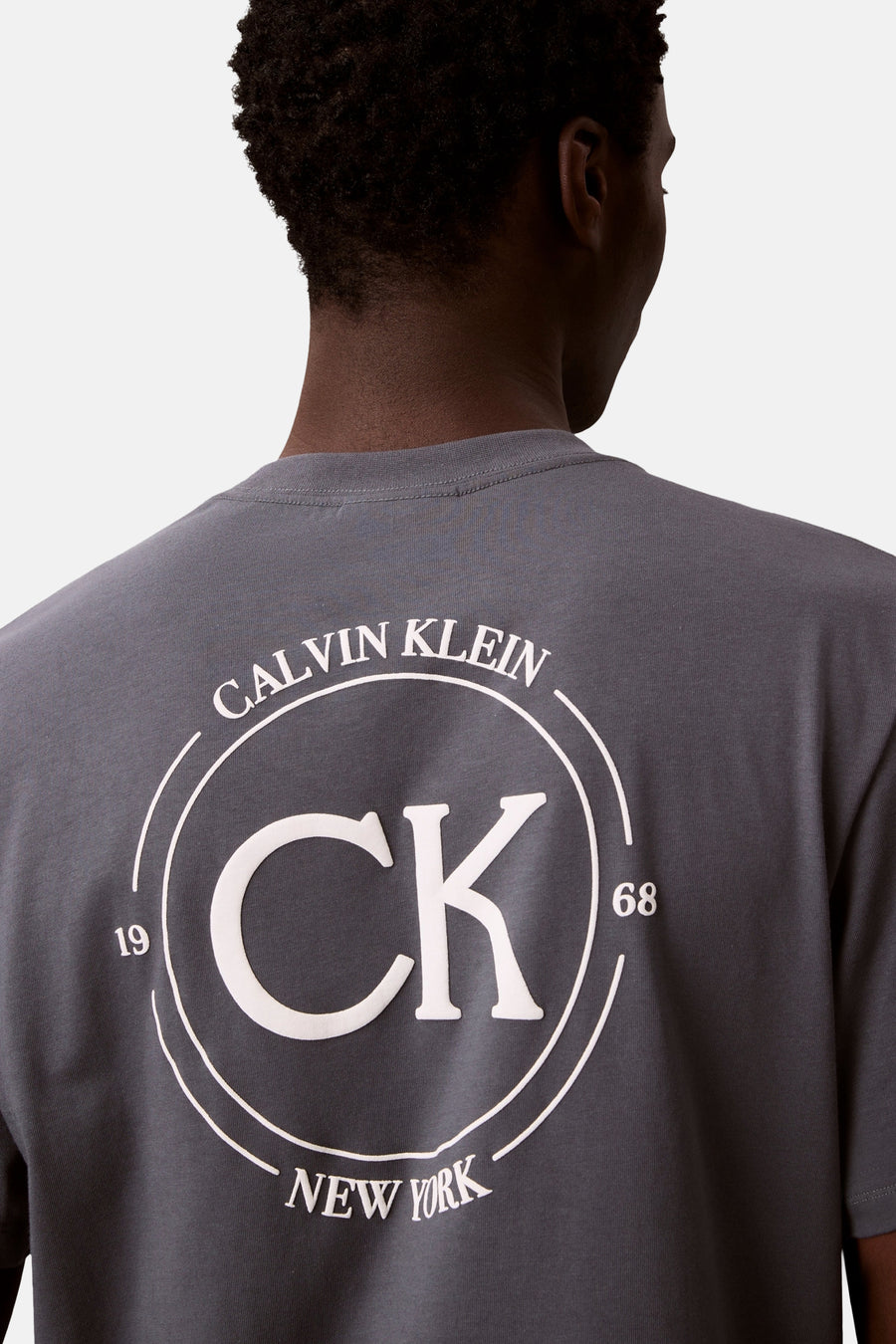 Grijs T-shirt met korte mouwen van Calvin Klein met cirkelvormig logo op de rug.