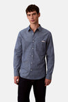 Chemise bleu à manches longues de Calvin Klein avec poche poitrine et texture subtile, portée avec un pantalon noir.
