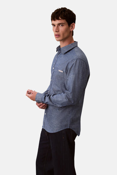 Chemise à manches longues bleue de Calvin Klein, avec poche poitrine boutonnée et détails texturés.