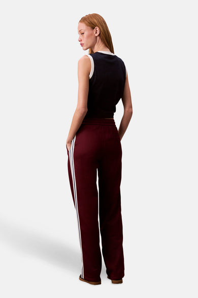 Bordeaux joggingbroek van Calvin Klein, met witte zijstrepen, gedragen met een zwarte tanktop met witte bies.