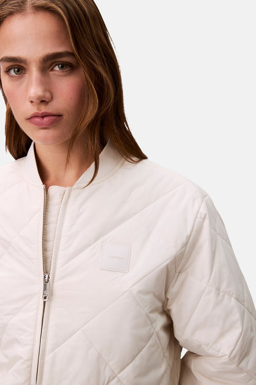 Veste courte écru de Calvin Klein, matelassée avec fermeture éclair argentée.