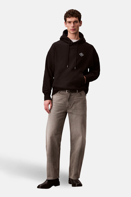 Zwarte Calvin Klein hoodie, gedragen met een wit T-shirt, een verbleekte spijkerbroek en zwarte leren enkellaarsjes.