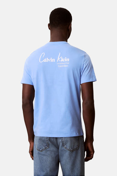 T-shirt bleu à manches courtes de Calvin Klein, avec un imprimé logo au dos, porté avec un jean.