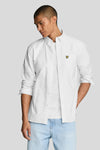 Chemise blanche à manches longues de LYLE & SCOTT, portée ouverte sur un t-shirt, avec un jean délavé.
