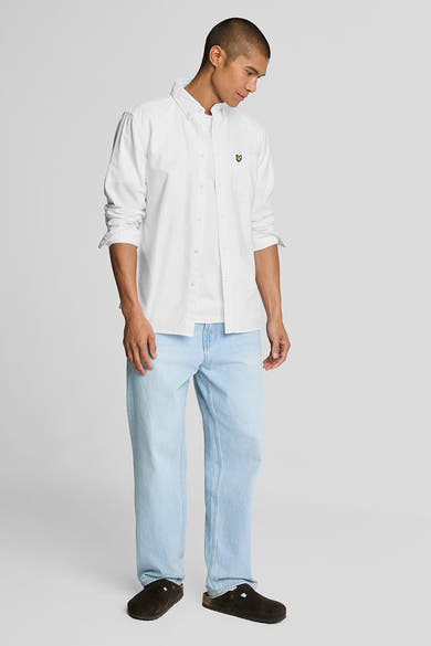 Chemise blanche à manches longues de LYLE & SCOTT, portée sur un t-shirt blanc et un jean bleu délavé.