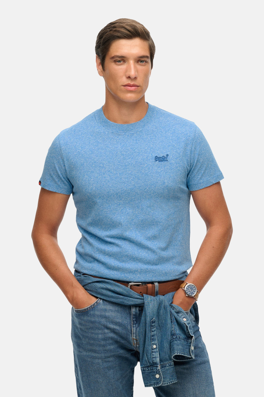 T-shirt à manches courtes bleu de Superdry, porté avec un jean et une chemise nouée à la taille.