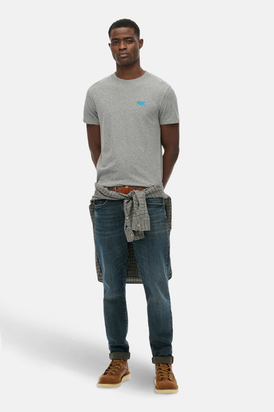 Grijs T-shirt met korte mouwen van SUPERDRY, gedragen met een geruit overhemd dat aan de taille is geknoopt en een blauwe jeans.