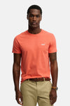 Koraalkleurig T-shirt met korte mouwen van SUPERDRY, gedragen met een chino en een gevlochten leren riem.