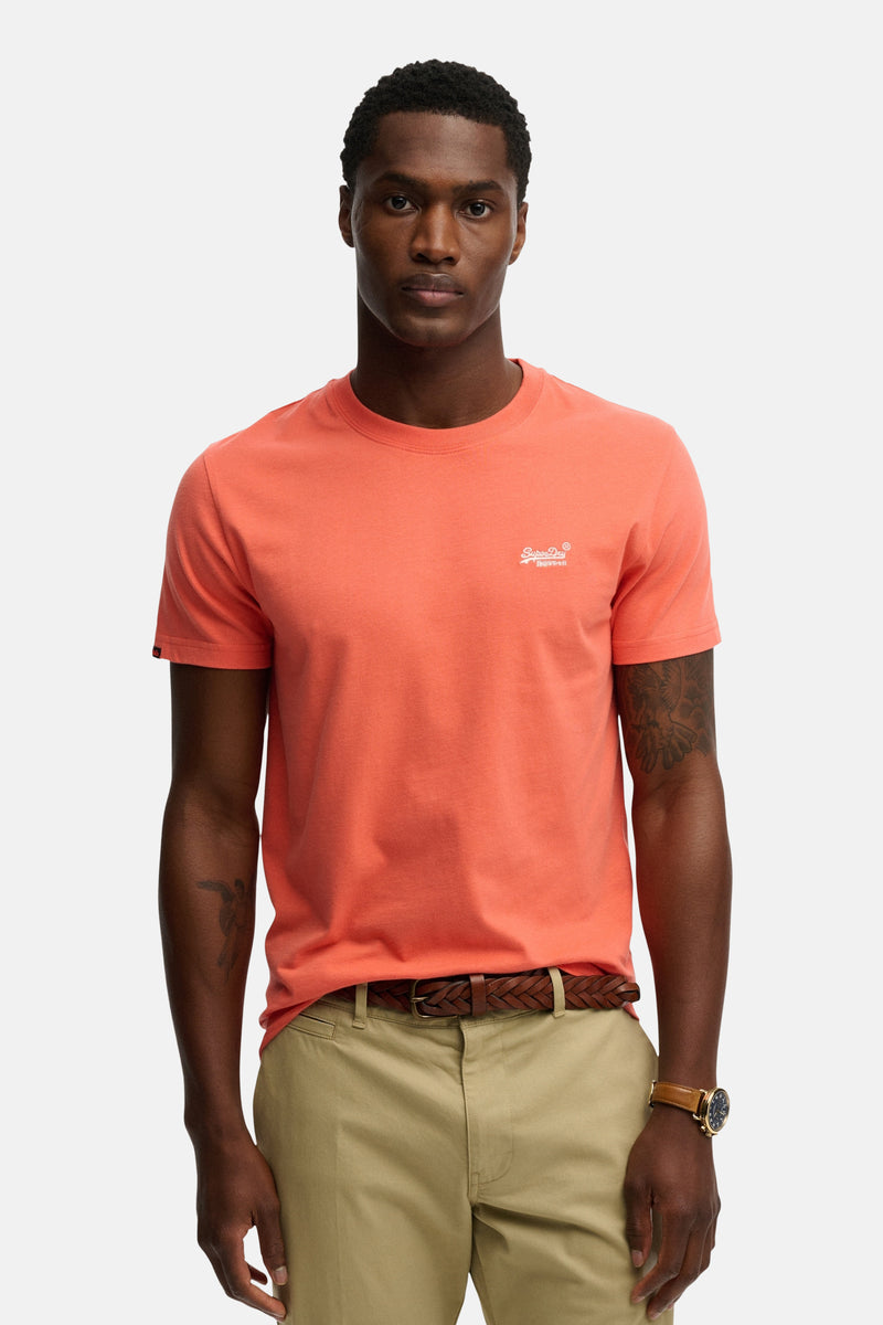 Koraalkleurig T-shirt met korte mouwen van SUPERDRY, gedragen met een chino en een gevlochten leren riem.