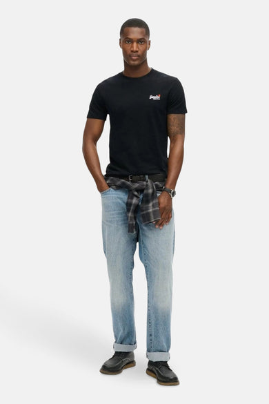 T-shirt noir à manches courtes de SUPERDRY, porté avec un jean bleu et une chemise à carreaux nouée.