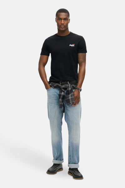 T-shirt noir à manches courtes de SUPERDRY, porté avec un jean bleu et une chemise à carreaux nouée.