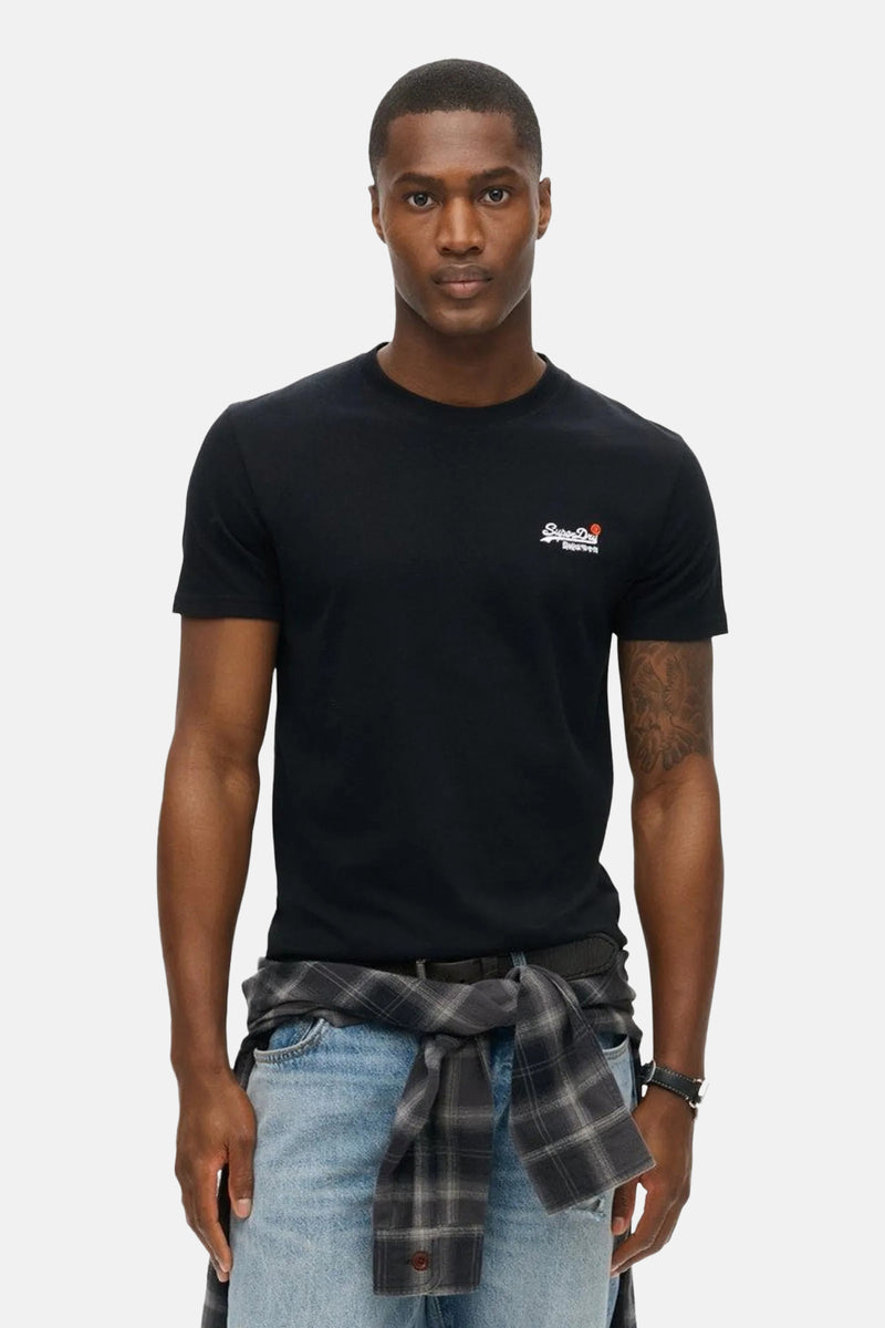 T-shirt noir à manches courtes de SUPERDRY avec logo brodé sur la poitrine, porté avec une chemise à carreaux nouée.