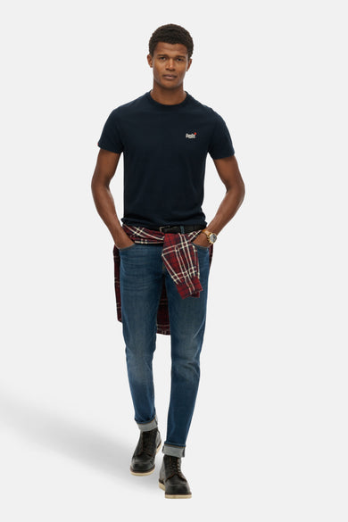 Blauw T-shirt met korte mouwen van SUPERDRY, gedragen met een geknoopt geruit overhemd en een spijkerbroek.