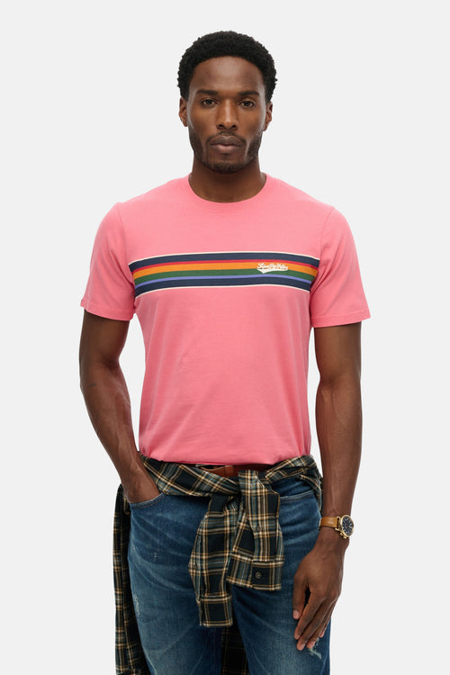 T-shirt à manches courtes rose SUPERDRY avec rayures horizontales multicolores, porté avec une chemise à carreaux nouée à la taille.