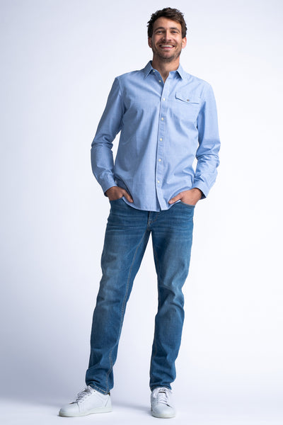 Chemise à manches longues bleue de Petrol Industries, portée avec un jean et des chaussures de sport blanches.