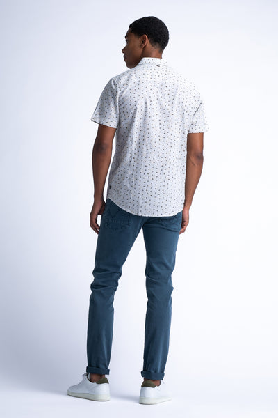 Chemise à manches courtes blanche à motifs de Petrol Industries, portée avec un pantalon et des chaussures blancs.