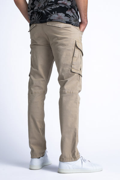 Pantalon cargo beige de Petrol Industries®, avec poches latérales, porté avec un t-shirt à fleurs et des baskets blanches.